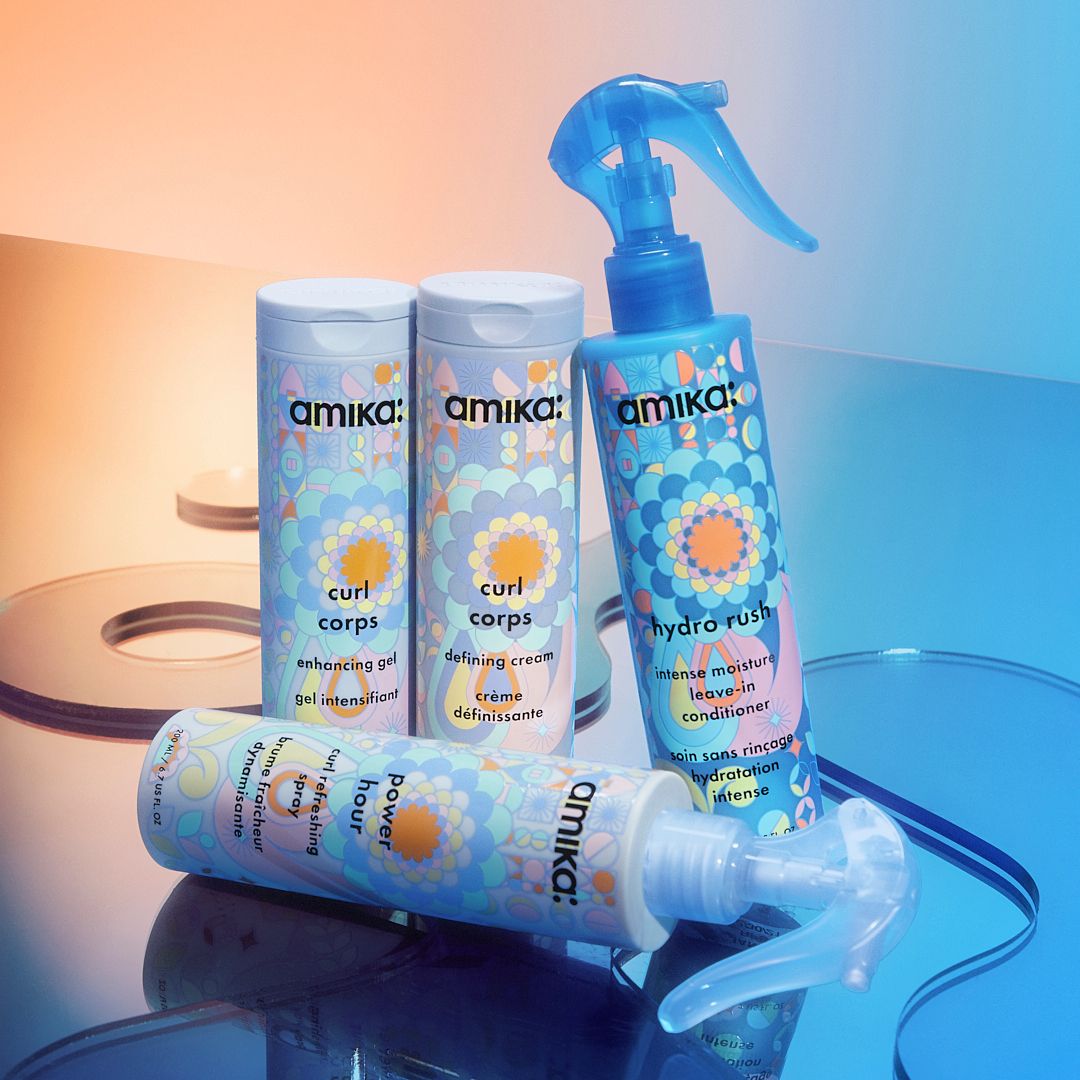 a collection of amika curl products, including curl corps enhancing gel and defining cream, hydro rush intense moisture leave-in conditioner and power hour curl refreshing spray