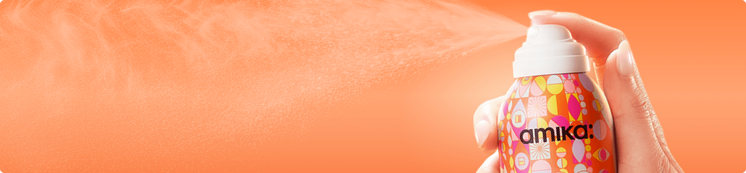 a bottle of amika dry shampoo spraying against an orange background
