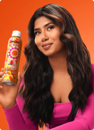 a model holds a bottle of amika perk up dry shampoo