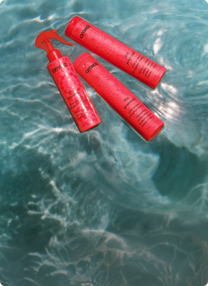 bottles of amika's the protector shampoo, conditioner, and treatment float in a swimming pool