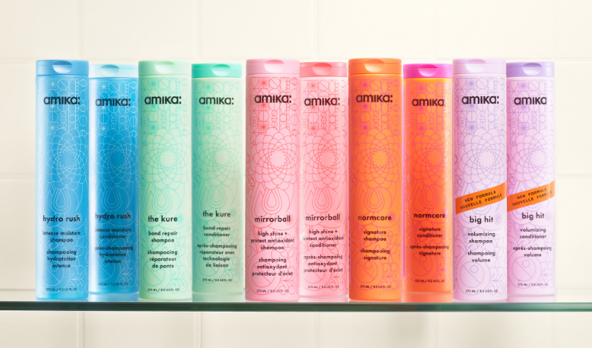 glass shelf showing amika shampoos and conditioners from left to right: hydro rush shampoo, hydro rush conditioner, the kure shampoo, the kure conditioner, mirrorball shampoo, mirrorball conditioner, normcore shampoo, normcore conditioner, big hit shampoo, big hit conditioner