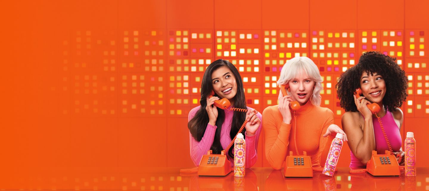 3 models talk on telephones and display amika perk up talc-free dry shampoo, perk up ultra oil control dry shampoo, and perk up plus extended clean dry shampoo.