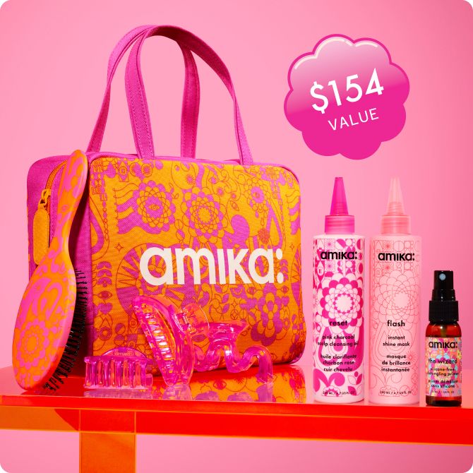 amika gift with purchase - image of an orange and pink patterned bag with a white amika: logo, a pink/orange hairbrush, 3 pink hair clips, and amika reset oil, flash mask, and the wizard primer. They all sit on an orange shelf against a pink background and a sticker reads "$154 value"