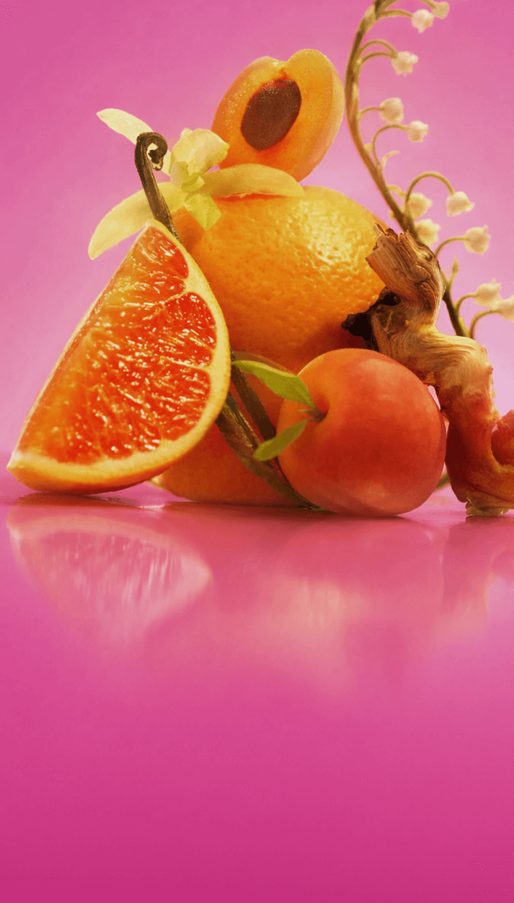 ingredient images of pink grapefruit, apricot, vanilla, lily of the valley and sandalwood on an pink background.