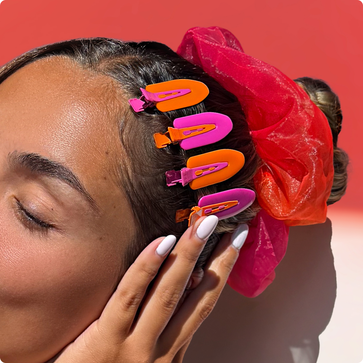 a model wears orange and pink clips and a chiffon orange-and-pink scrunchie in their hair