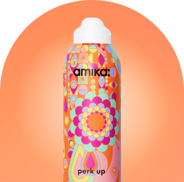 a bottle of amika perk up dry shampoo against an orange background