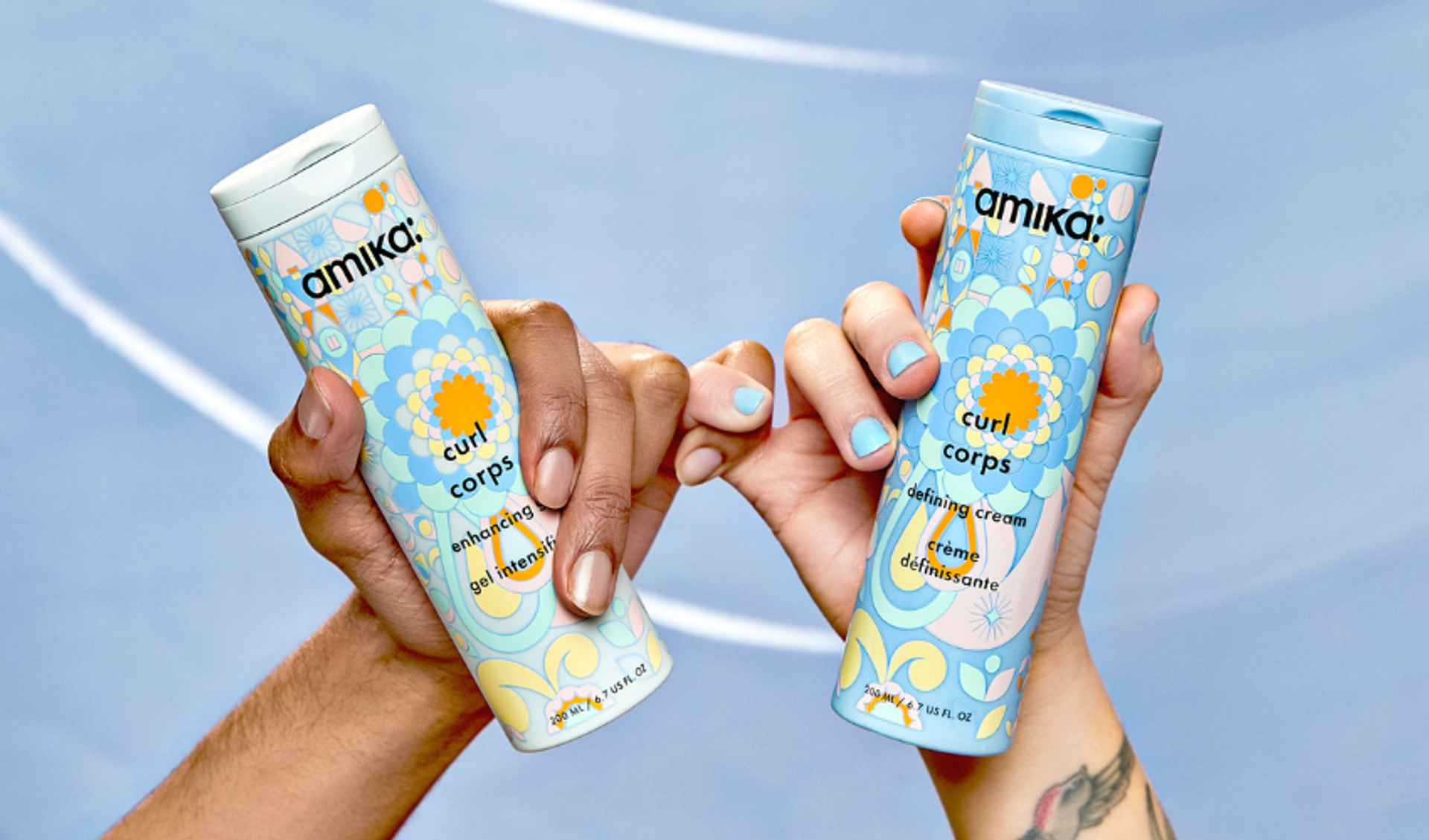 two hands linking pinkies holding amika curl corps gel and defining cream