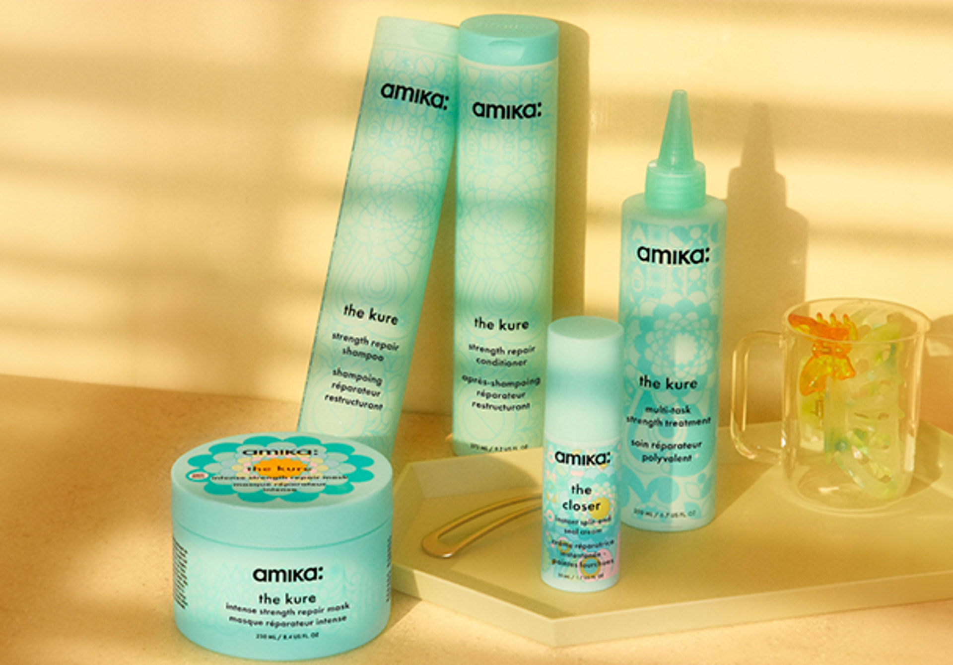 bottles of amika products for strength repair against a yellow background