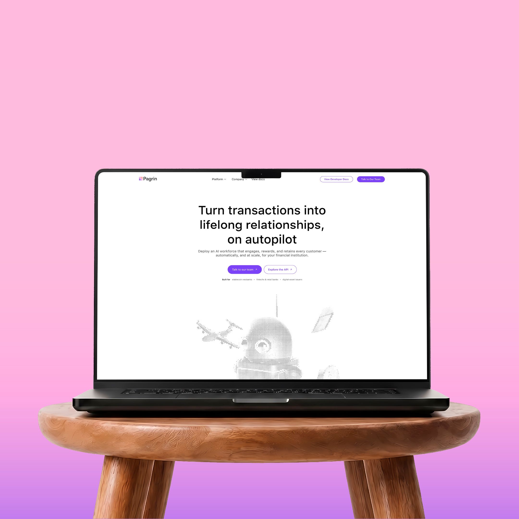 The Pagrin homepage on a laptop resting on a wooden stool against pink.