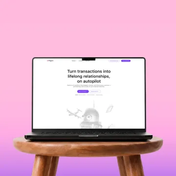 The Pagrin homepage on a laptop resting on a wooden stool against pink.