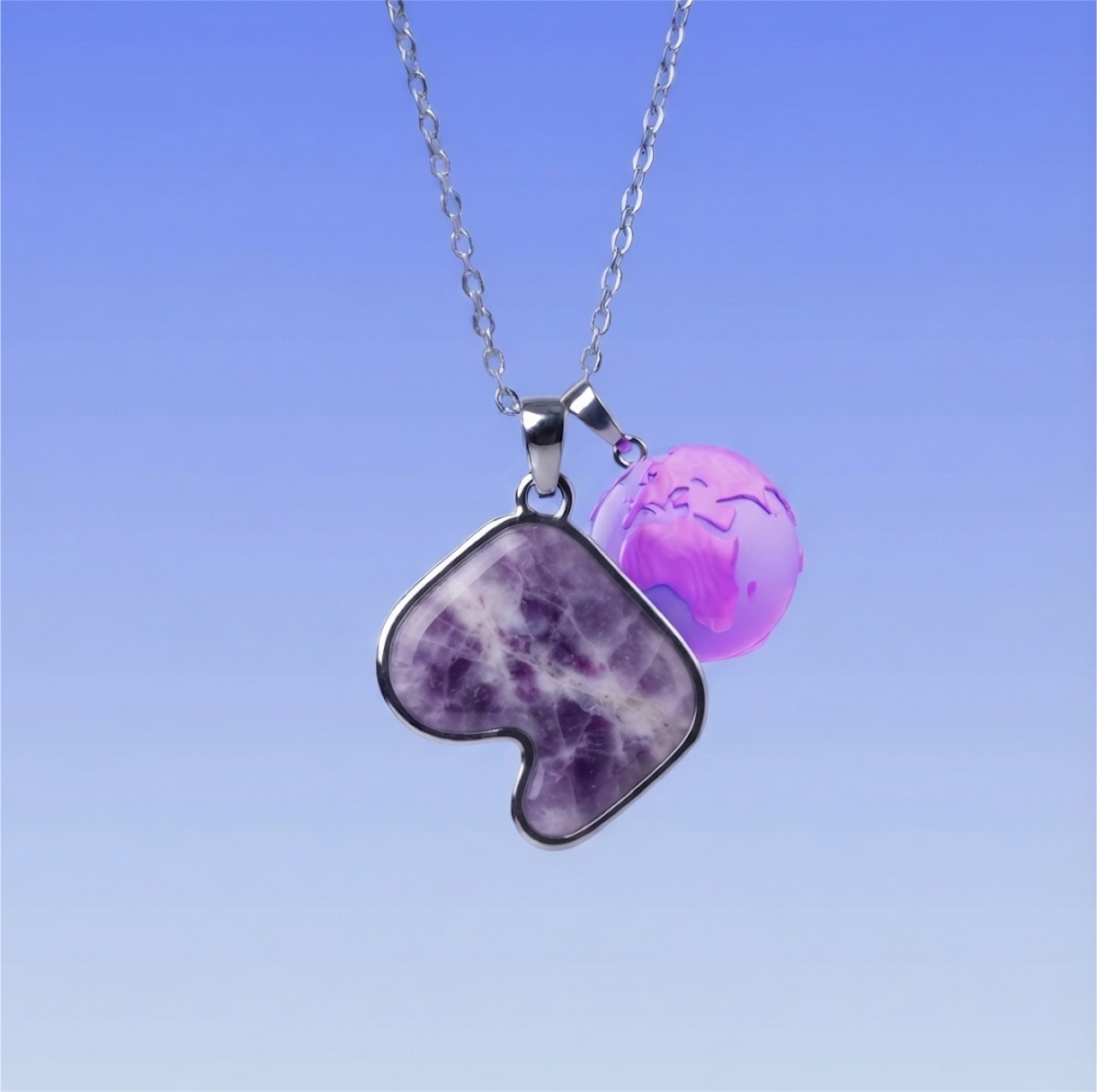 A silver necklace with an amethyst pendant cut in the shape of the Safiri mark, against a blue sky.