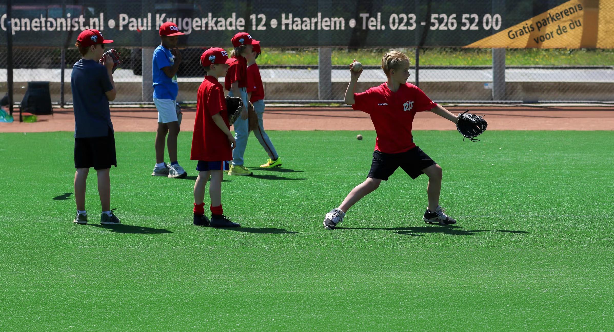 Jeugdtraining bij DSS Haarlem honkbal met speler die een worp maakt op het veld.