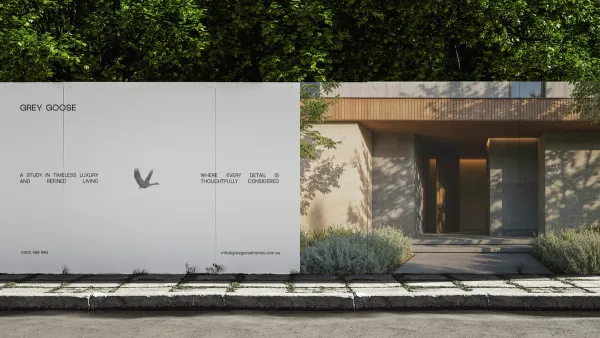 Grey Goose site hoarding in pale grey with the goose mark, running along the street in front of a finished stone home