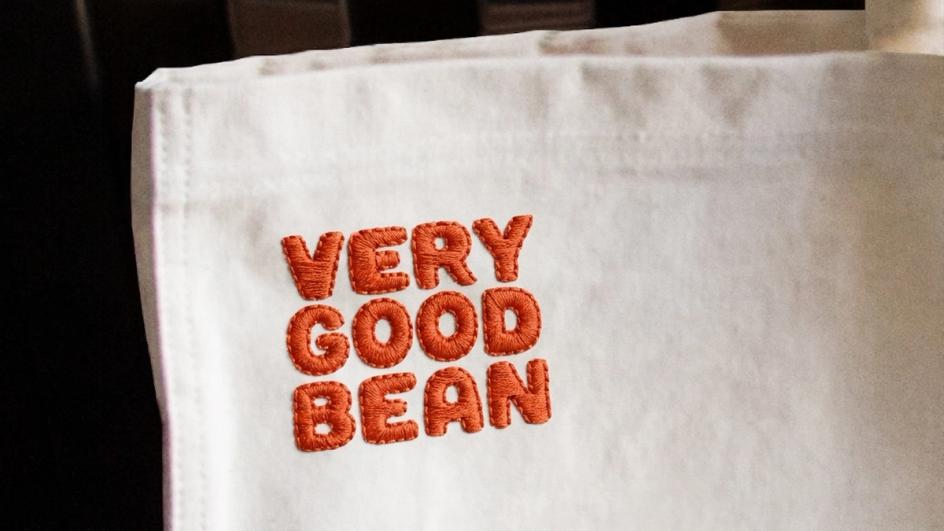 The wordmark embroidered in orange thread on white cotton