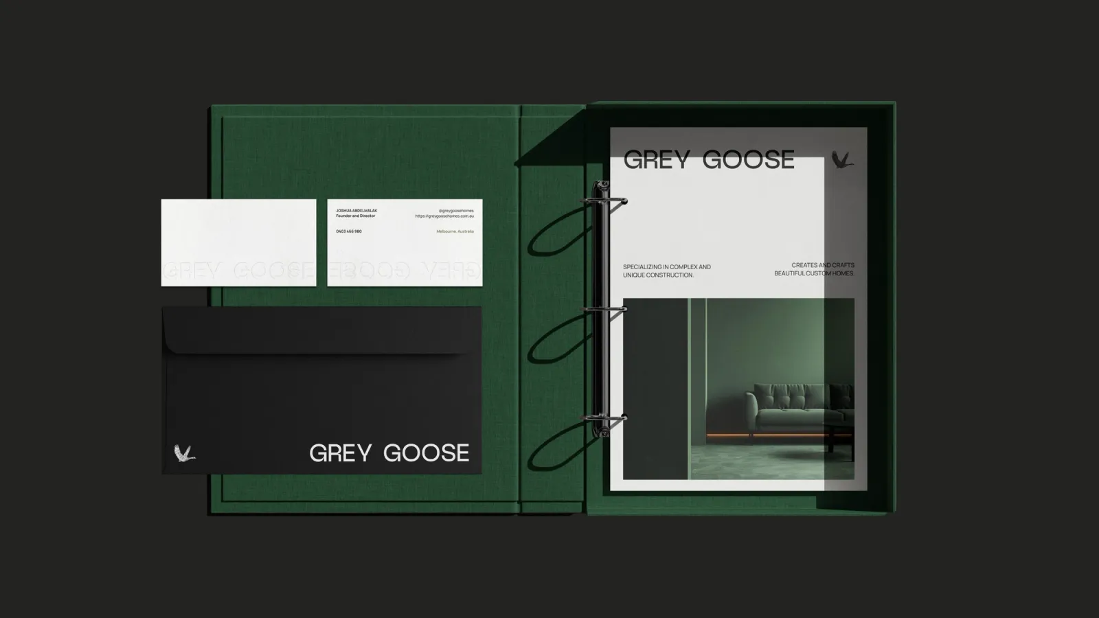 The Grey Goose stationery set laid out on charcoal: business cards, a black envelope and the green capabilities binder