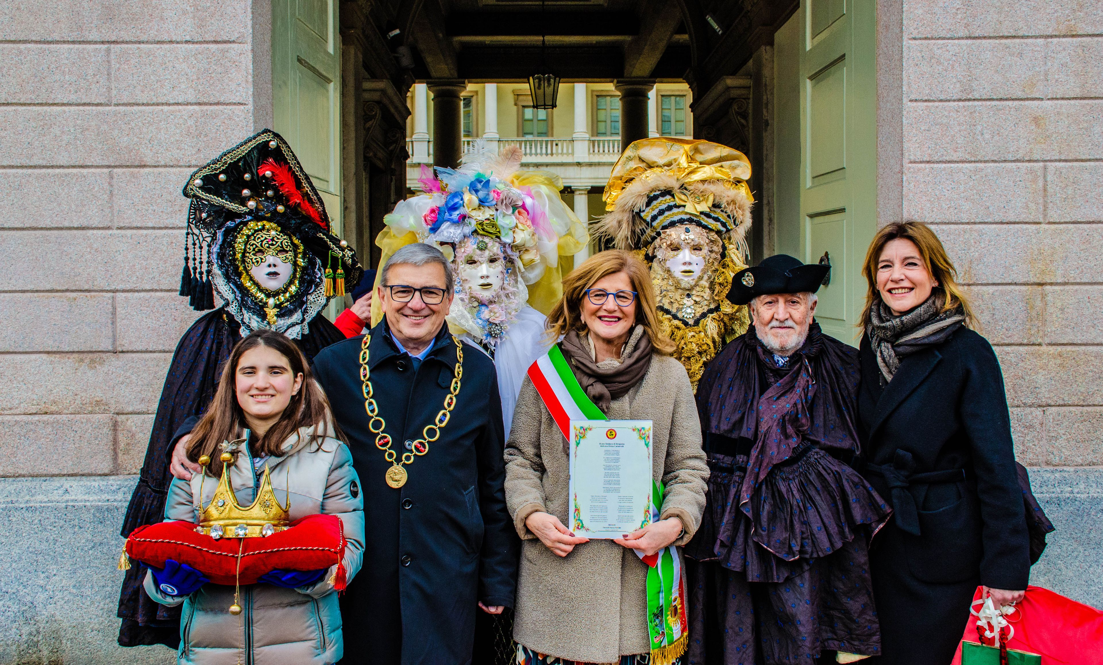 Il Duca del Ducato di Piazza Pontida accanto alla Sindaca di Bergamo, circondati da maschere tipiche del folklore bergamasco, in un momento istituzionale e celebrativo.