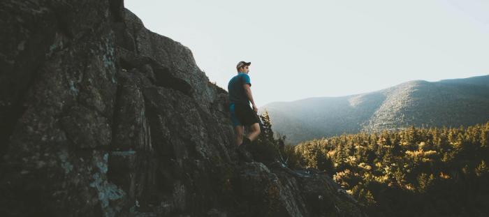 A man hiking on a rocky cliff on a sunny day
