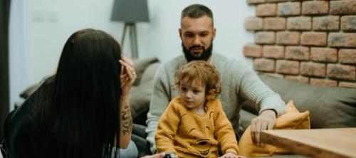 a man and a woman sitting on a couch next to a little girl