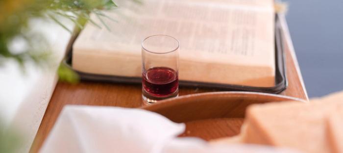 tray with small glass of wine next to bible