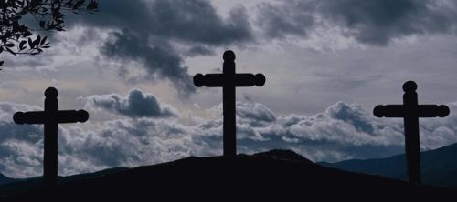 Three crosses in silhouette against a cloudy sky.