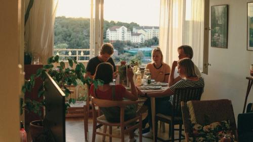 Five young people having lunch together in an apartment.