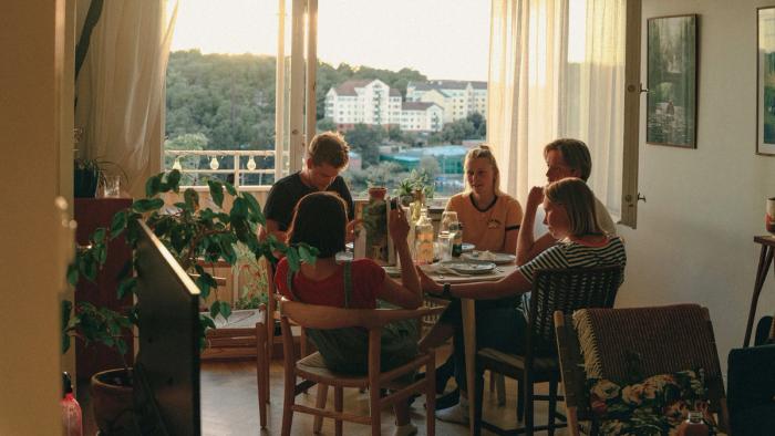 Five young people having lunch together in an apartment.