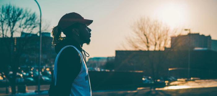 Man in red hat looking profile in front of cityscape at sunset