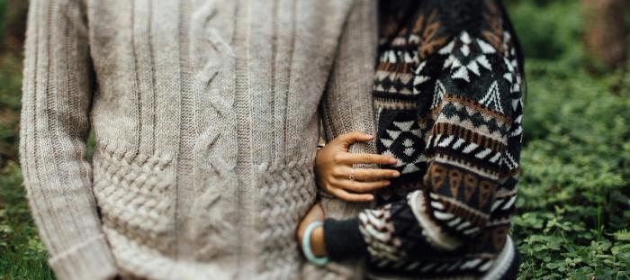 woman in patterned sweater holding man's arm in beige sweater