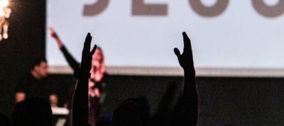 hands raised in worship in front of power point screen
