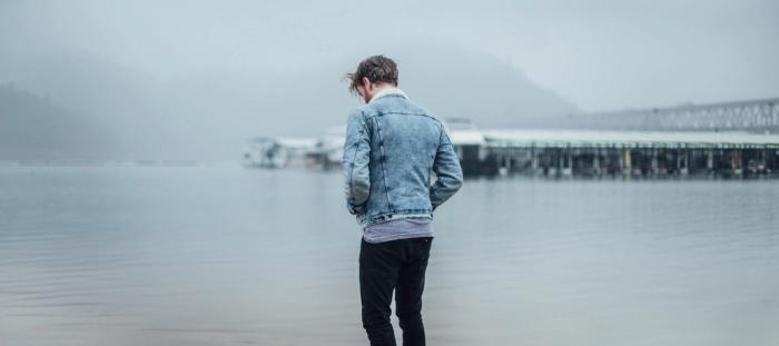 man in blue denim jacket standing on shore