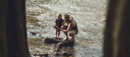 3 women sitting on rock in river during daytime