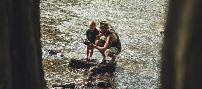 3 women sitting on rock in river during daytime