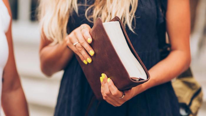 A woman holding a leather bound Bible.