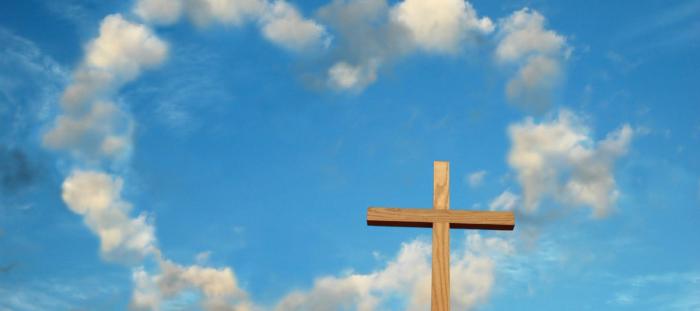 wood cross in front of blue sky with clouds