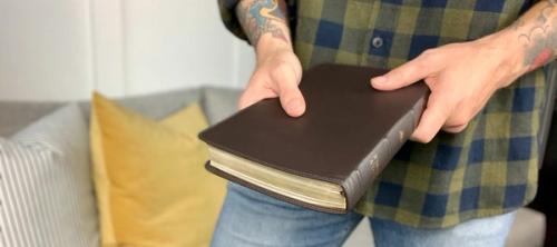 person in blue denim jeans holding a bible
