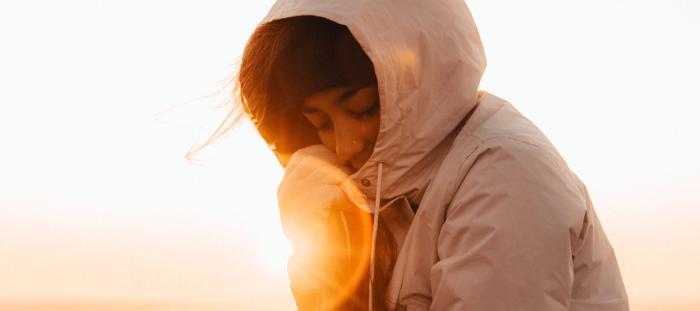 woman in a hoodie with sun shining in background