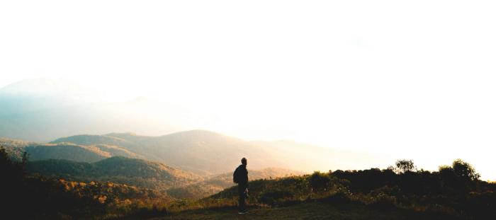 man standing near mountain under cloudy sky at daytime