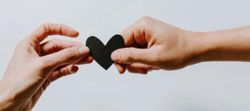 hands holding a paper black heart
