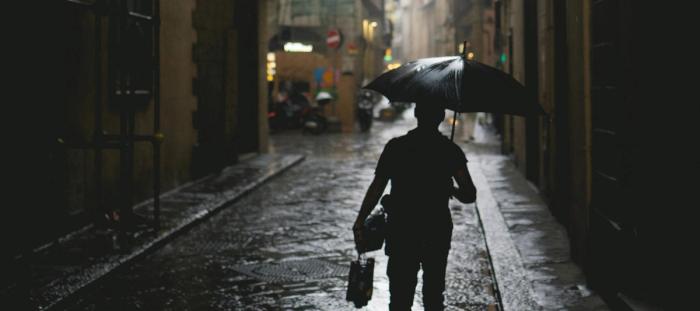 A person walking down a street holding an umbrella