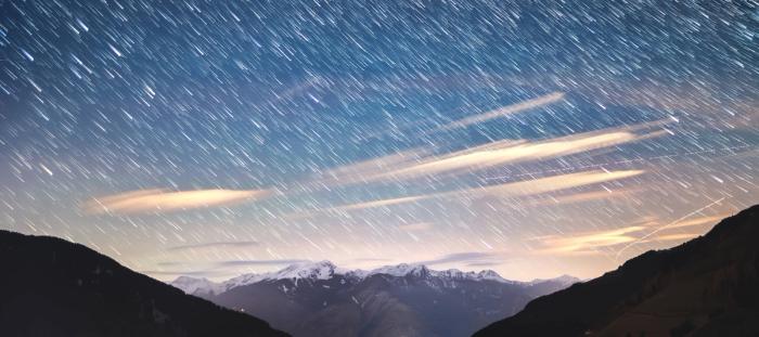 meteor shower in daylight over snowy mountains