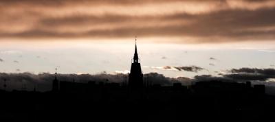 dark steeple and building within a cloudy sky