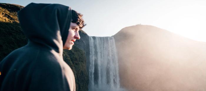 a man standing in front of a waterfall
