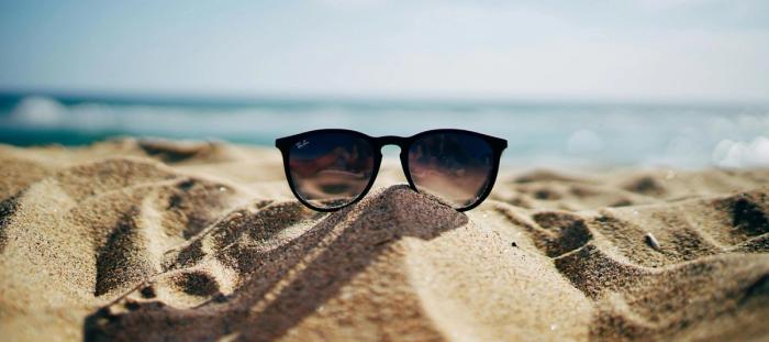 black Ray-Ban Wayfarer sunglasses on beach sand