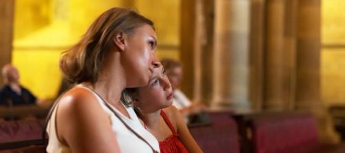 A mother and daughter sitting together in a church pew.
