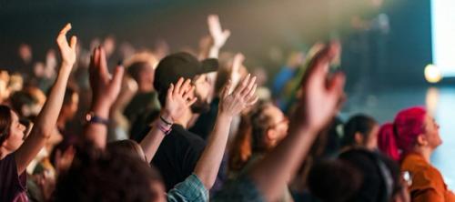 a crowd of people with their hands in the air