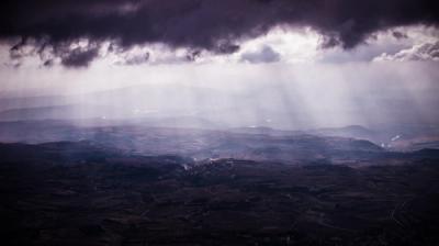 dark clouds with sun peering over landscape