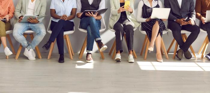 people lined up in chairs with views of legs crossed