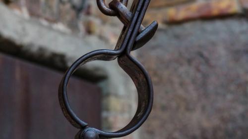 A metal shackle hanging from a chain.