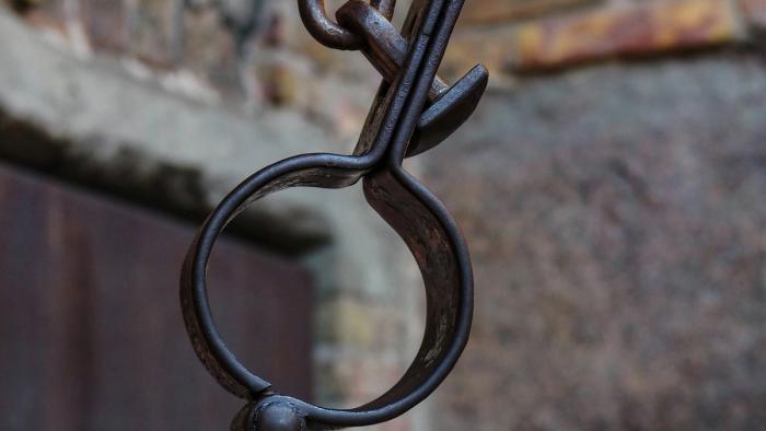 A metal shackle hanging from a chain.