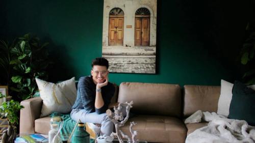 A smiling young man relaxing on a couch in a stylish living space.